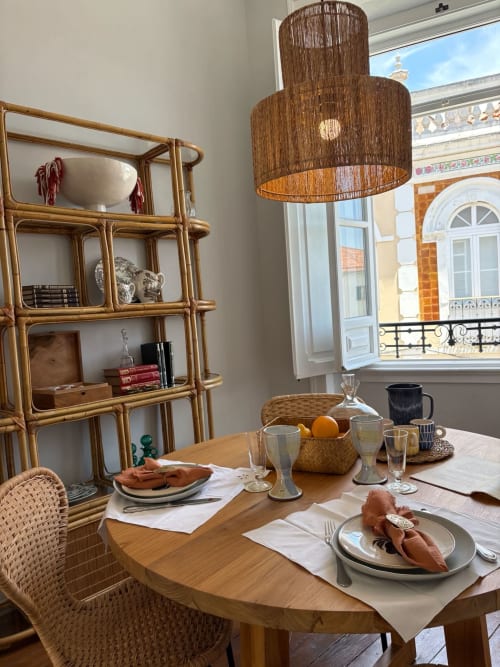 Elegante sala de jantar em Casa Amanhada em Grândola com mesa de madeira, cadeiras de vime e vista da cidade pelas portas francesas