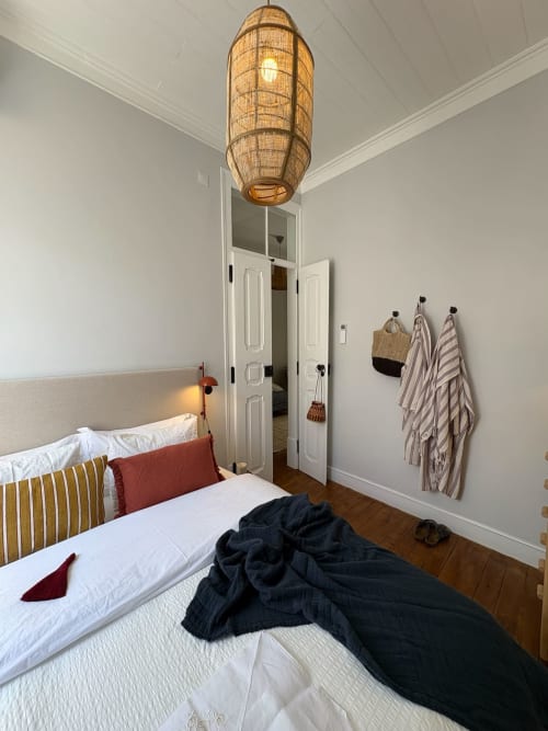 Quarto moderno na Casa Amanhada, Grândola com luminária de vime, paredes brancas, cama com listras e piso de madeira