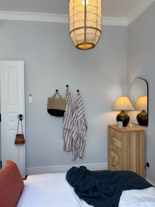 Quarto moderno na Casa Amanhada em Grândola com cômoda de madeira, luminária pendente e roupa de cama listrada