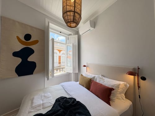 Quarto luminoso na Casa Amanhada em Grândola com cama, arte abstrata e varanda com vista para a cidade