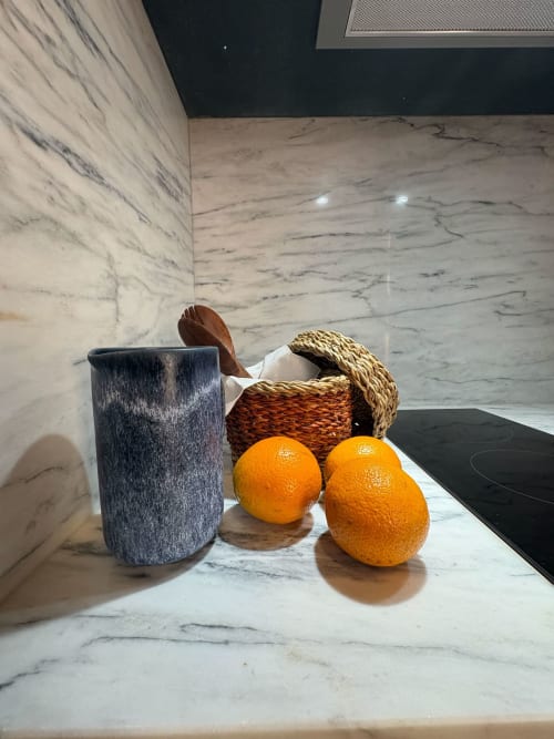 Balcão de cozinha em mármore na Casa Amanhada com laranjas frescas, vaso azul e cestos trançados
