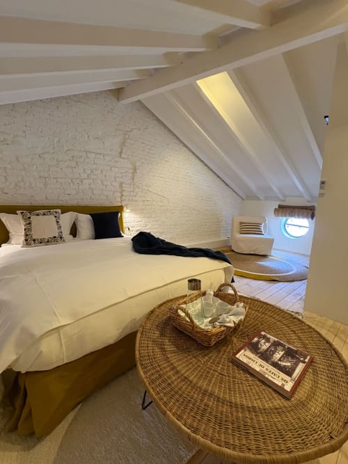 Quarto moderno no sótão da Casa Amanhada, Grândola, com vigas brancas, mesa de vime e vista para a cidade