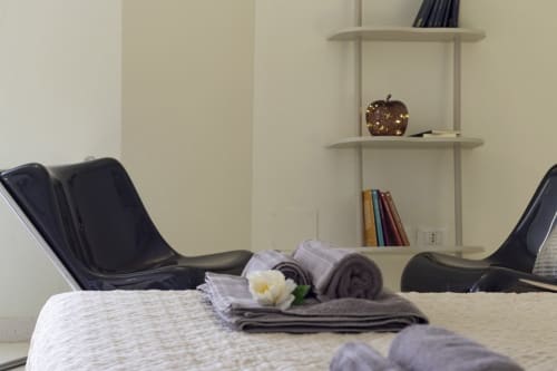 Spa retreat setup at Pescara INN with rolled towels, white flower, modern black chairs, and wall shelving with decor