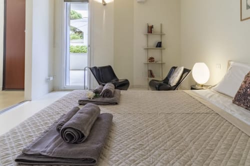 Spacious bedroom at Pescara INN Pineta Retreat with garden view, rolled towels on bed, modern furnishings and shelving