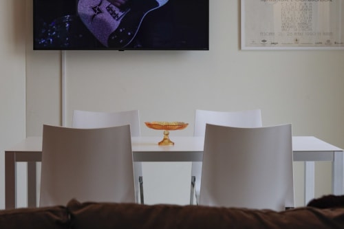 Modern dining area at Pescara INN with white chairs, small table, and amber glass bowl centerpiece