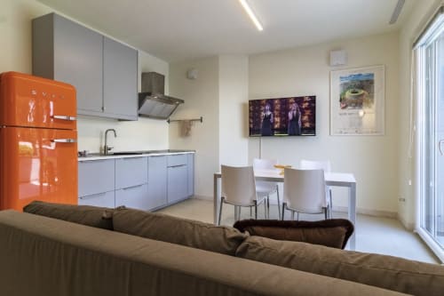 Modern open-plan kitchen and dining area at Pescara INN Pineta Retreat with orange Smeg fridge, blue cabinetry, and garden