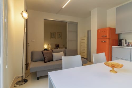 Modern studio apartment at Pescara INN with open kitchen, dining area, orange retro refrigerator, and bedroom nook with gray