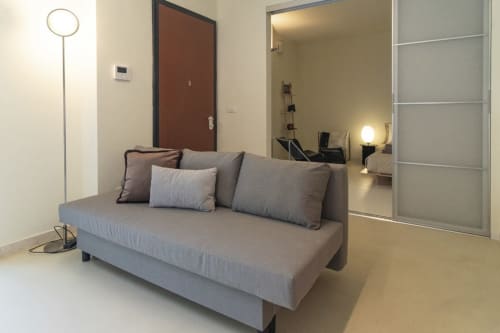 Modern studio apartment at Pescara INN with gray sofa, floor lamp, brown door, and mirrored wardrobe in minimalist