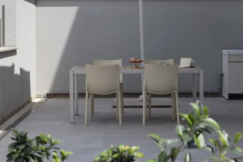 Modern dining area at Pescara INN Pineta Retreat with cream chairs, table, and gray walls overlooking a garden patio