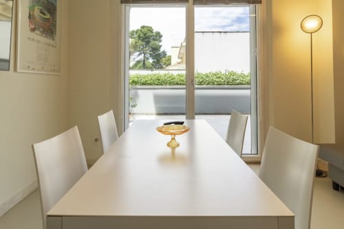 Modern dining room at Pescara INN with white table, chairs, and garden view through floor-to-ceiling windows at Pineta
