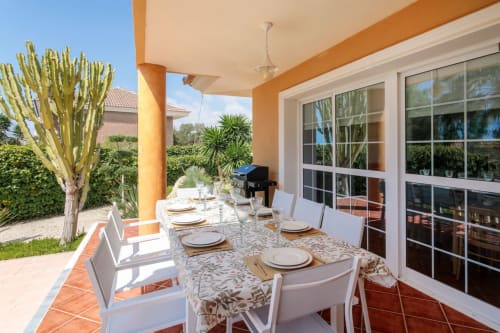 Patio del apartamento Wellhome Alicante con comedor, vistas al mar y plantas tropicales