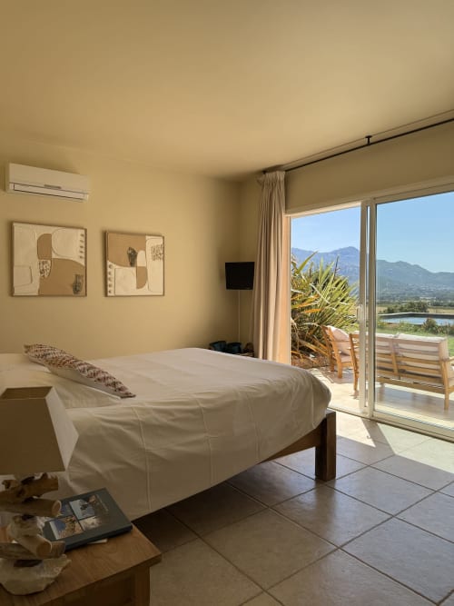 Chambre lumineuse avec terrasse vue mer à la Villa La Vista, Lumio. Lit blanc, panorama montagneux, équipements modernes.
