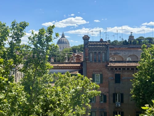 Vista della cupola della Basilica di San Pietro e dei monumenti storici di Roma dalla finestra della suite Enjoy Vatican, con verdure