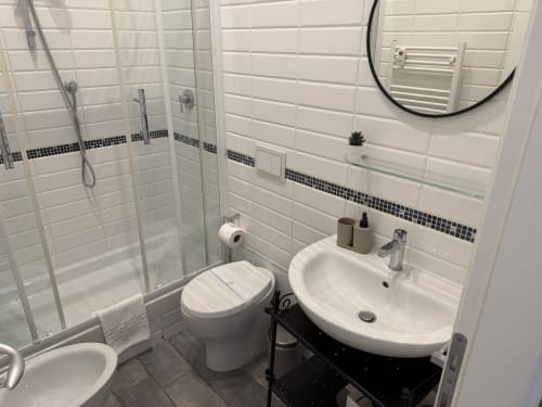 Bagno moderno all'Enjoy Vatican Rome con pareti in piastrelle bianche, doccia in vetro, lavabo bianco, WC e vanity in nero