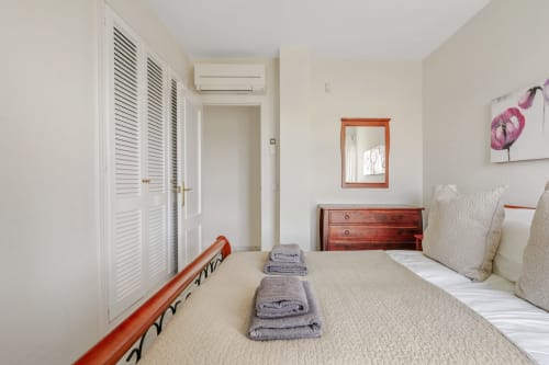 Nowoczesna sypialnia w apartamencie w Mijas z widokiem na morze, drewniana komoda, białe szafy z żaluzjami i łóżka bliźniacze