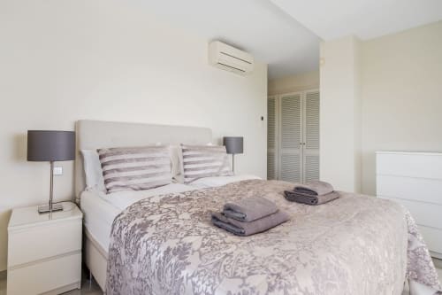 Nowoczesna sypialnia w apartamencie HomyMarbella Mijas z klimatyzacją, poduszkami w paski i dekoracyjną pościelą