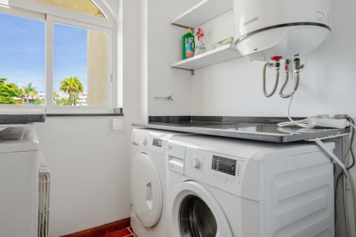 Nowoczesna pralnia z pralką, podgrzewaczem wody i regałami w apartamencie HomyMarbella w Mijas, Hiszpania