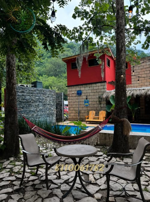 Patio exterior con hamaca, asientos y casita roja en el resort de montaña Tierra Cielo & SoLuna en Potrero de Serna, México