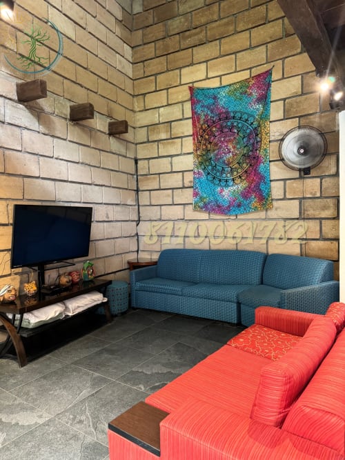 Apartamento Casona en Tierra Cielo & SoLuna con sofá verde azulado, asientos coral, TV, tapiz colorido y muros de ladrillo en Potrero de