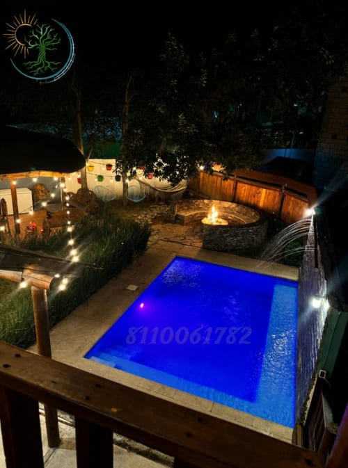 Patio nocturno en Tierra Cielo & SoLuna en Potrero de Serna con piscina iluminada, fogata y ambiente montañoso