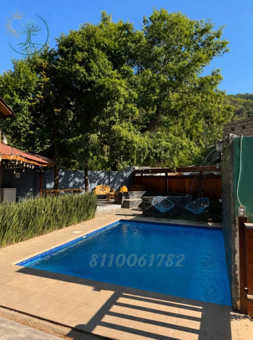 Piscina azul rodeada de patio de terracota, árboles frondosos y cómodas áreas de descanso en Tierra Cielo & SoLuna en Potrero de