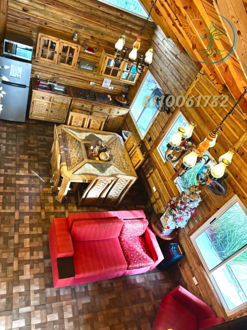 Acogedora sala de estar con sofá rojo, muebles de madera y vistas a la montaña en el hotel Tierra Cielo & SoLuna en Potrero de Serna,