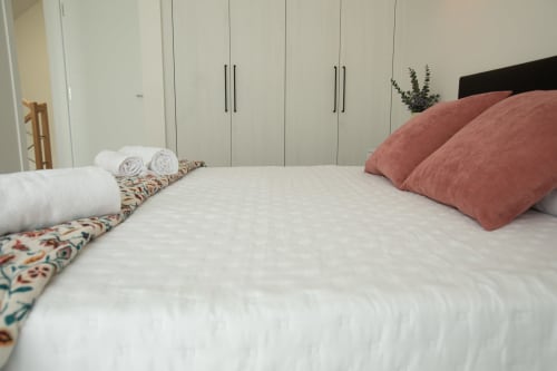 Dormitorio moderno en Villa Gozamena 167 con cama blanca, almohadas terracota y armarios empotrados en Fuerteventura