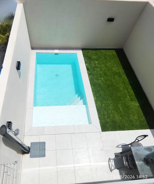 Vista aérea de Villa 167 Gozamena en Fuerteventura con piscina turquesa, terraza blanca y patio con césped artificial