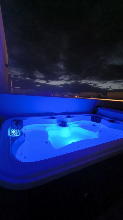 Bañera de hidromasaje iluminada al atardecer en villa de Fuerteventura con vistas al océano y cielo al atardecer