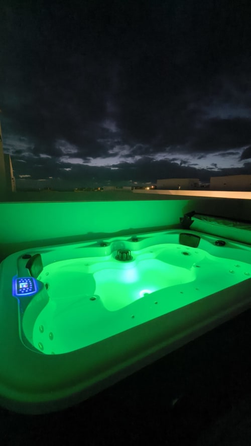 Jacuzzi iluminado en verde al atardecer con cielo tormentoso, Villa Gozamena en Fuerteventura