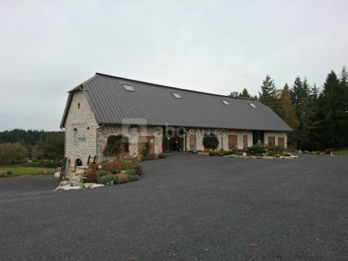 Hôtel La Romanée Sofia à Rosiers-d'Égletons, bâtiment en pierre avec toit métallique foncé et allée