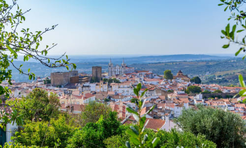 Vista aérea da histórica cidade medieval de Portalegre com torres do castelo e catedral, vales verdejantes além