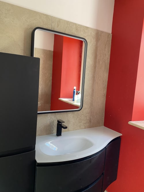 Modern bathroom sink with black faucet and rounded mirror at Le Clos Saint Maurin B&B in Saint Maurin