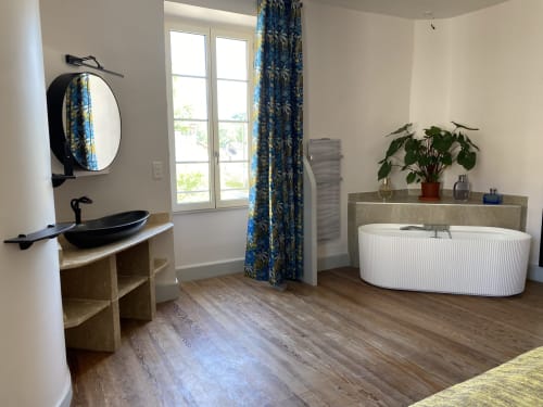 Modern bathroom at Le Clos Saint Maurin, Saint Maurin with black vessel sink, freestanding tub, and blue patterned curtains