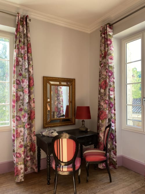 Elegant bedroom nook at Le Clos Saint Maurin with floral curtains, black desk, and striped chairs