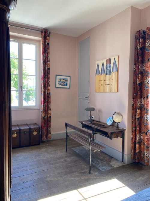 Salon de détente du Clos Saint Maurin aux murs roses, bureau, malle vintage et vue sur le jardin