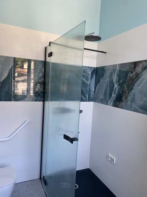 Salle de bain moderne au Clos Saint Maurin avec douche à l'italienne, robinetterie noire et carreaux muraux à motifs