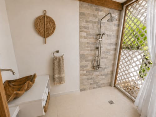 Salle de bains Faupapa à la Fare Tihi Moana avec douche à l'italienne, art mural en feuilles tressées et vues sur la porte à treillis à Uturoa, Polynésie française