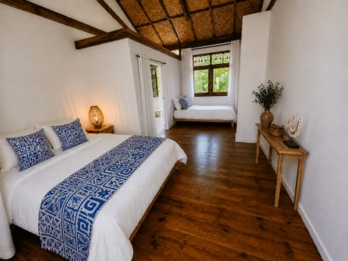 Spacieuse chambre Taurua au Fare Tihi Moana à Uturoa avec poutres en bois, literie aux motifs bleus et vue sur l'océan