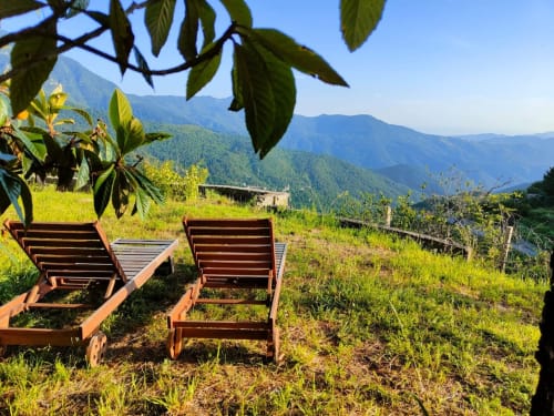 Deux chaises longues en bois offrent une vue sur les montagnes verdoyantes près de Bajardo, Italie, à l'hôtel Allegria Affittacamere