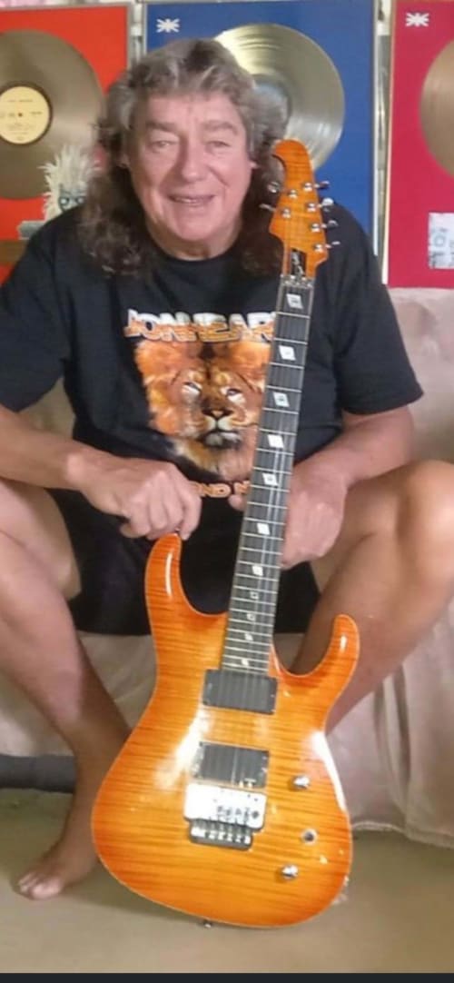 Musician with long hair holding orange electric guitar at Bennachie Hotel, Kemnay, Aberdeenshire