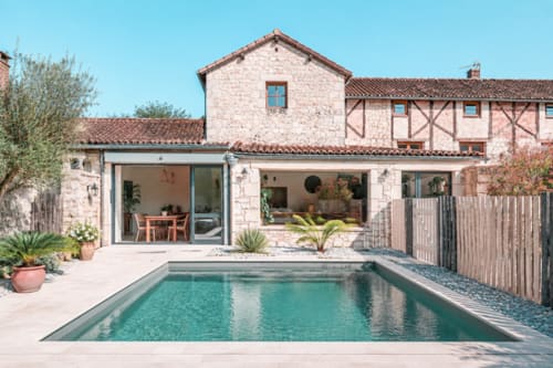 Le Clos Divin, gîte à Forges : piscine turquoise, terrasse moderne et architecture en pierre sous ciel bleu