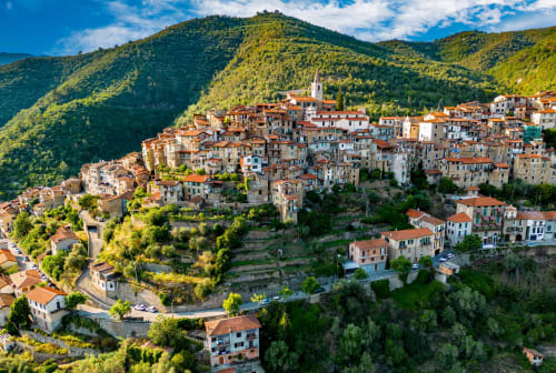 Village de Bajardo perché sur une colline avec maisons colorées, clocher d'église et montagnes forestières, Italie