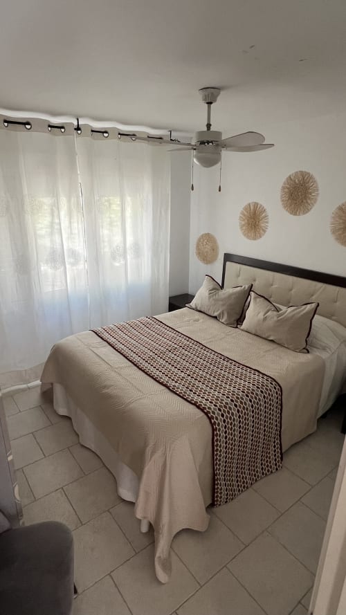 Luminosa habitación en la cabaña Las Casitas de Noe en Layos con cama matrimonial, ventilador de techo y cortinas translúcidas