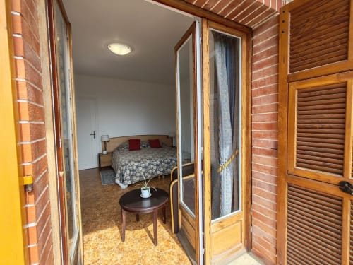 Entrée de chambre à l'Allegria Affittacamere à Bajardo avec portes miroir, mobilier en bois et lit aux oreillers rouges