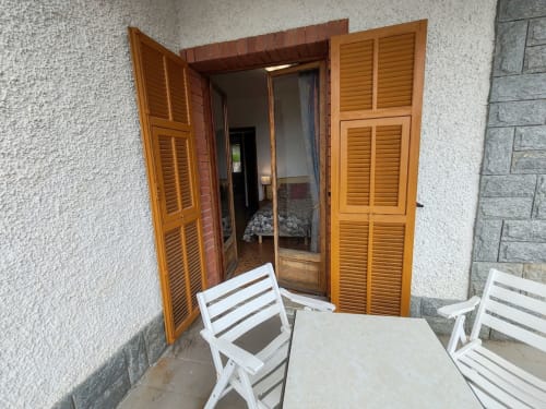 Coin salon sur la terrasse d'Allegria Affittacamere à Bajardo avec volets en bois et chaises blanches