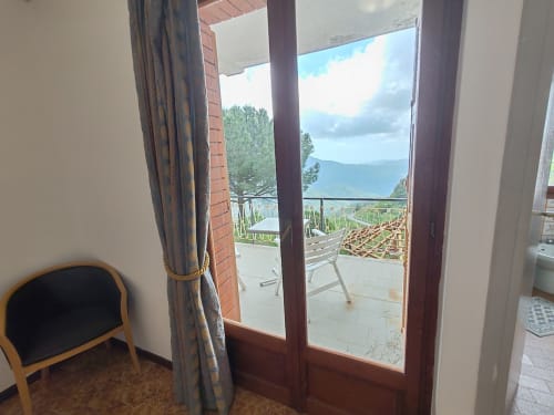 Vue de la terrasse d'Allegria Affittacamere à Bajardo avec montagnes, vignobles et chaise