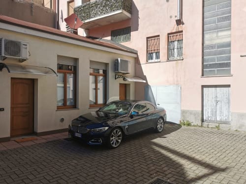Black BMW parked in paved courtyard of The Kraken Inn, Bergamo urban apartment building