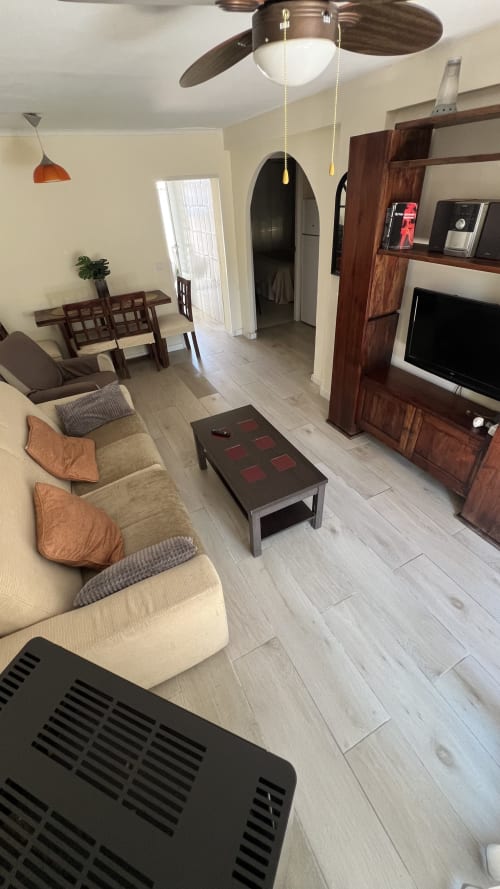 Amplia sala de estar en la cabaña Las Casitas de Noe en Layos con cómodos asientos, TV, muebles de madera y ventilador de techo