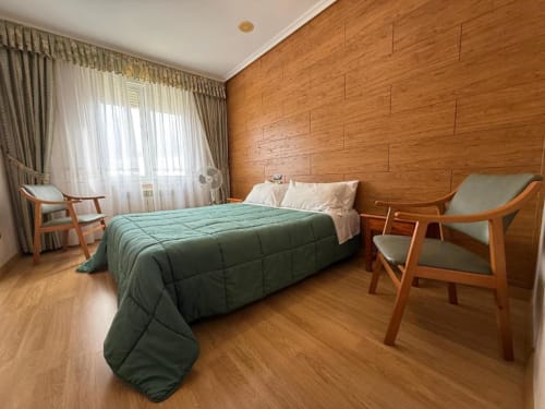 Habitación doble espaciosa en Hostal Asber de Zamora con paredes de madera, cama queen, sillas de mediados de siglo y calidez en los tonos